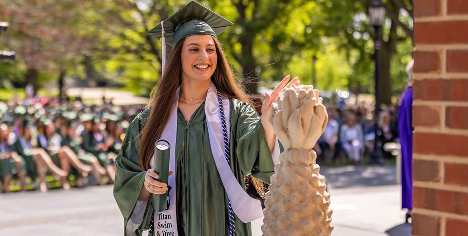 Graduate touching pineapple during commencement