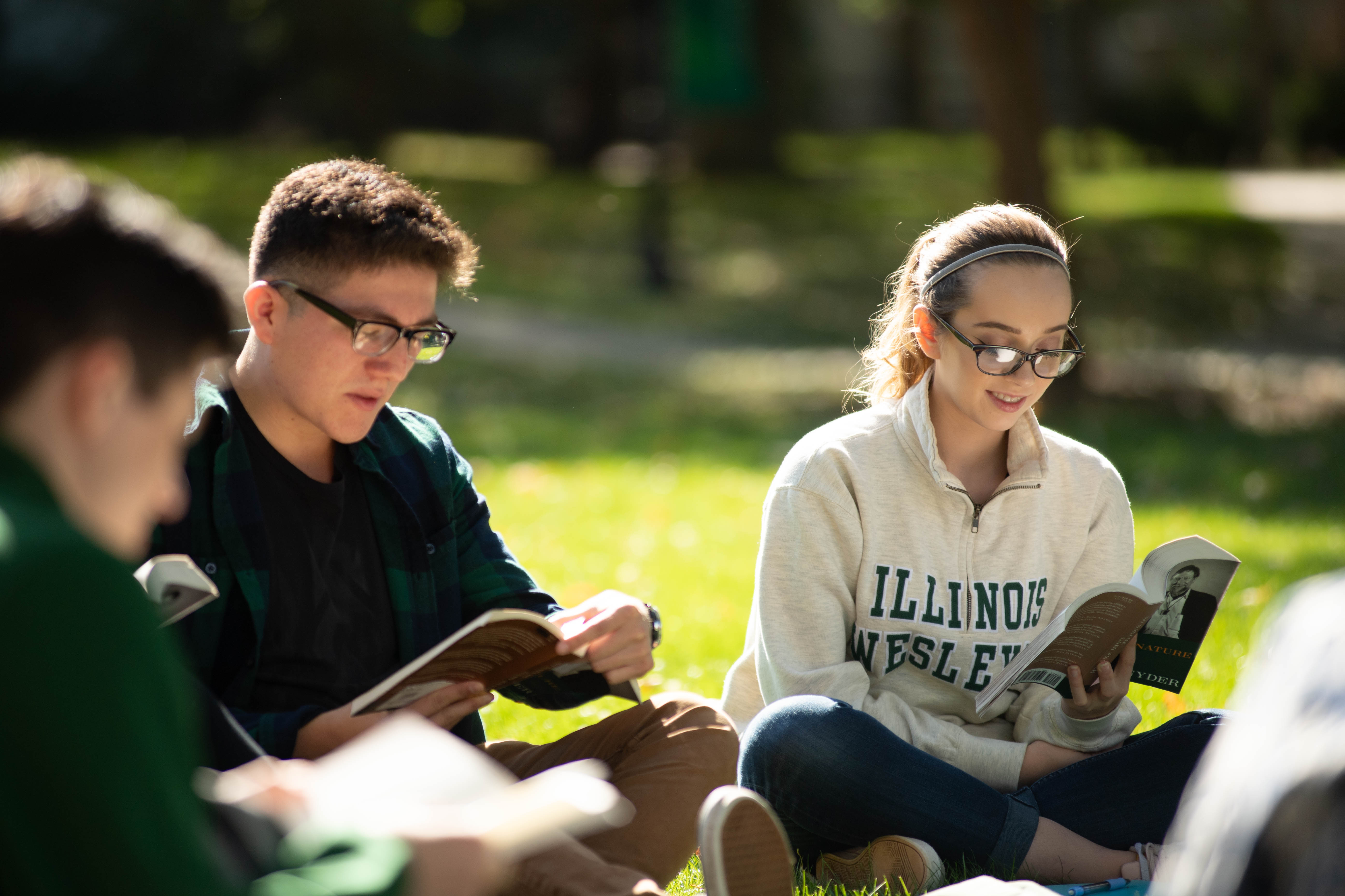 Student reading book and studying on quad.