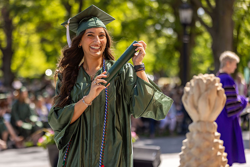 Student during Commencement with diploma and pineapple statue