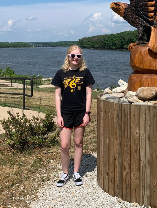 Female student wearing sunglasses standing in front of a river