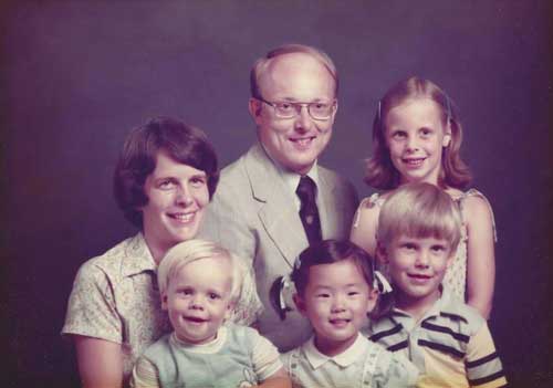 Dr. Judith Eckerle ’98 (bottom center) poses for a family portrait with her adopted family.