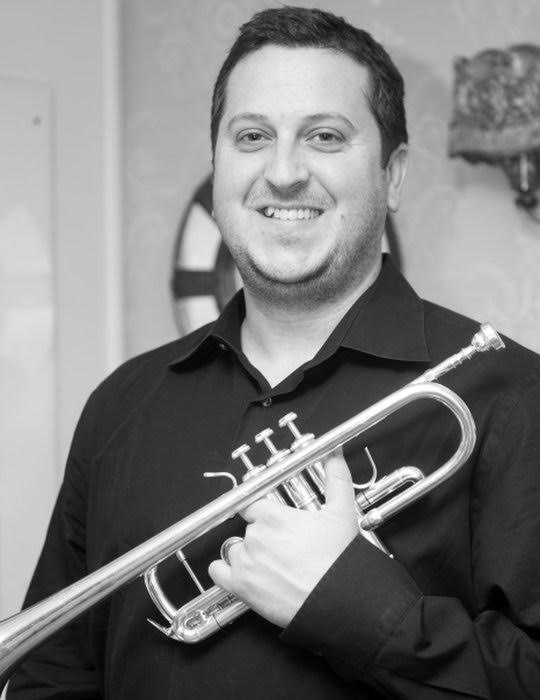 Ryan Hobbs smiles while posing with his trumpet