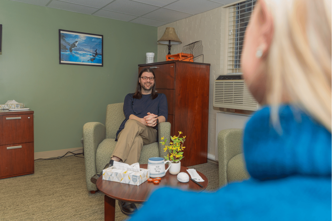 Director of Counseling and Consultation Services Jojo Mitchell sitting and speaking with a staff member in the foreground