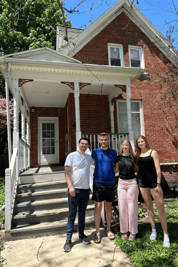 students standing in front of brick house