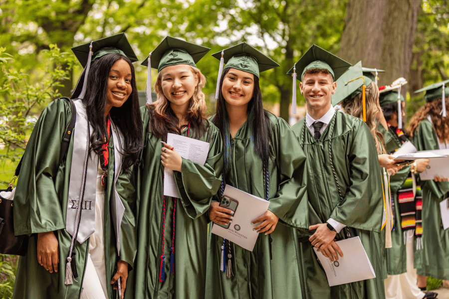 Four IWU graduates pose before the 2024 commencement ceremony