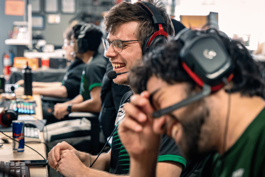 students laugh together at computers with headsets