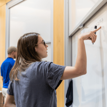 Student points to equation written on white board