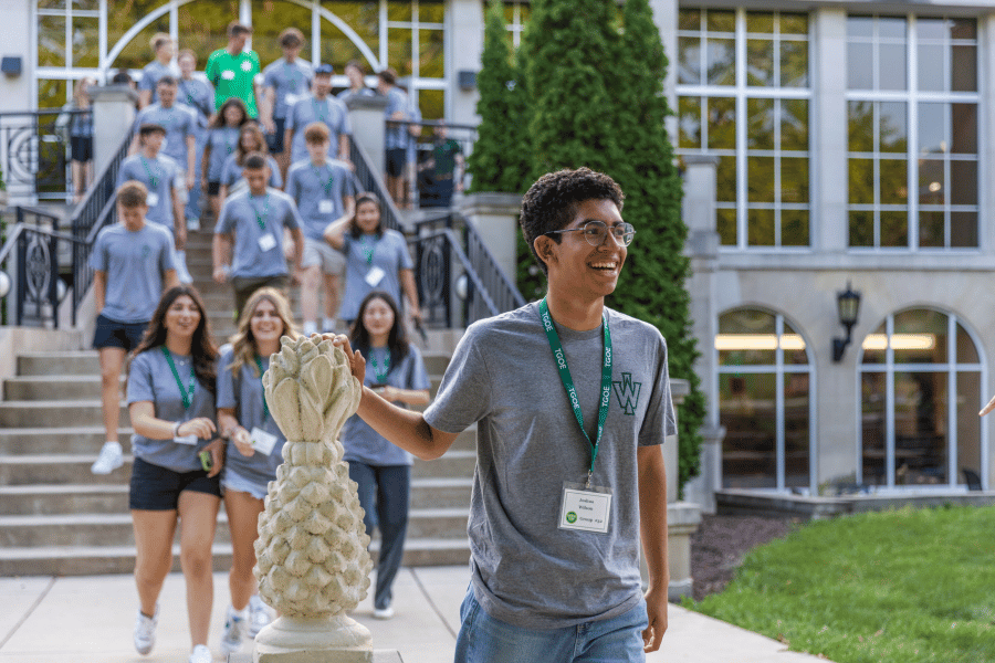 Students leavng the Memorial Center and touching a stone pineapple at base of stairs