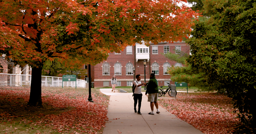 students shaking hands under fall folliage on the quad at Illinois Wesleyan University