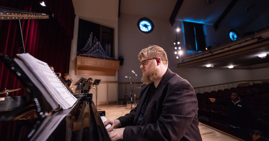 An IWU student plays a jazz piece while seated at a piano in Presser Hall at IWU