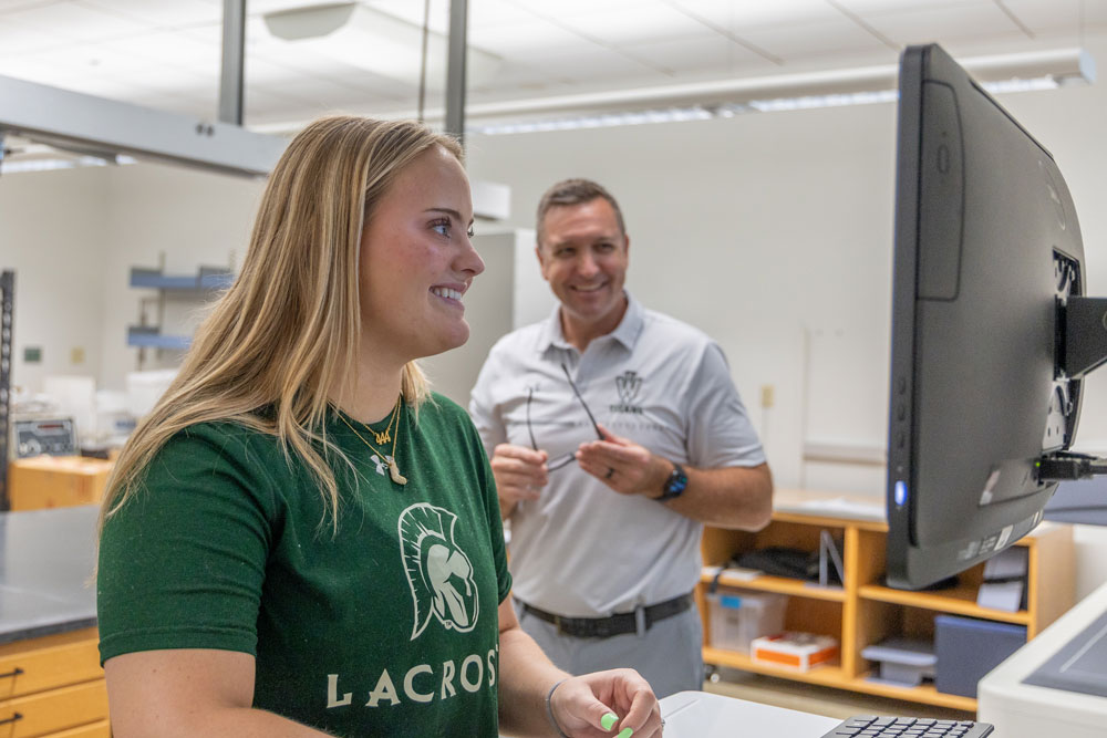 Student looking at a computer while a professor looks on