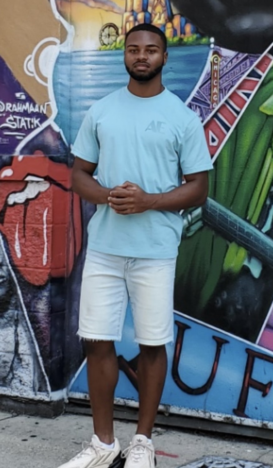 Student standing in front of a colorful outdoor mural