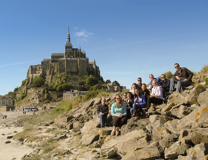 group sitting outside on rocks in front of castle