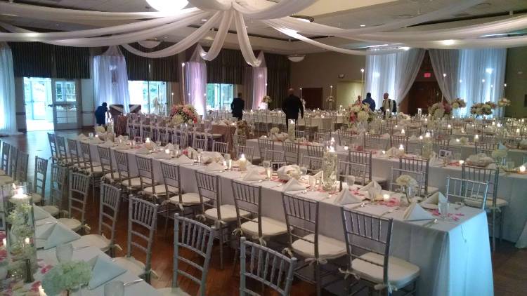 Round tables are spread out in Young Main Lounge, each topped with water glasses, place settings, and candles.